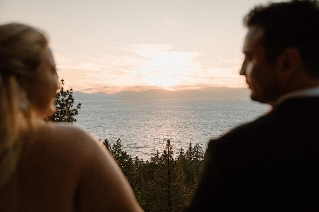 bride and groom out of focus with Lake Tahoe in the background at sunset