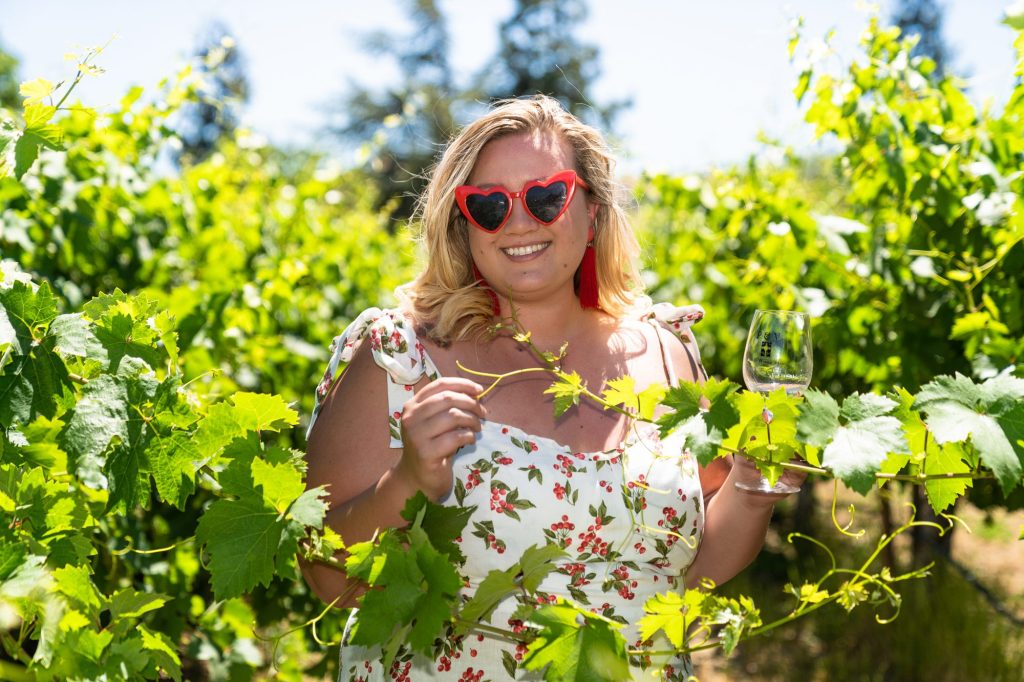 Gabbi stands in a cherry dress at a vineyard in Morgan Hill, California