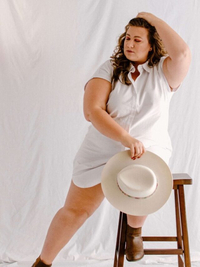 woman poses on stool in white button down dress